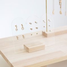 a wooden table topped with lots of jewelry on top of display cases next to a white wall