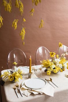 the table is set with yellow flowers and place settings