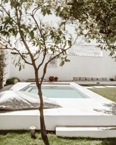 a small pool in the middle of a yard with trees and lawn furniture around it