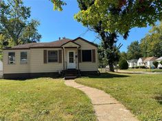 a small house sitting in the middle of a grass covered yard next to a tree