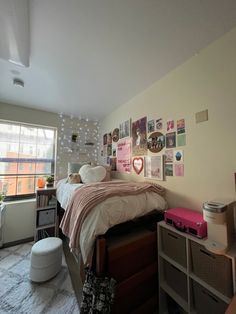 a bed room with a neatly made bed and lots of pictures on the wall above it