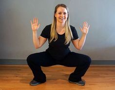 a woman sitting in a yoga pose with her hands up to the side and smiling