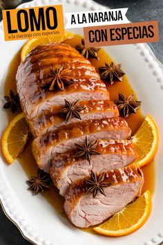 sliced pork with oranges and spices on a white plate next to an orange slice