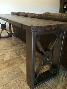 a wooden table sitting on top of a tile floor next to a brown leather couch