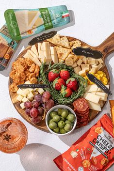 an assortment of cheeses, crackers, and fruit on a wooden platter