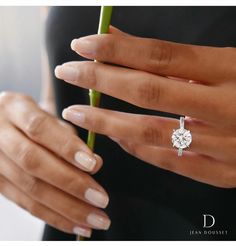 a woman's hand holding a flower with a diamond ring on her finger,