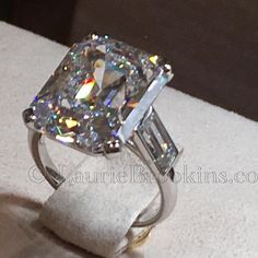 a fancy diamond ring with two baguettes on it's sides, sitting on top of a white cloth