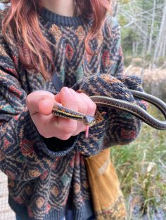 a woman holding a small snake in her hands