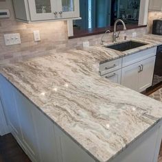 an image of a kitchen setting with granite counter tops and white cabinets in the background