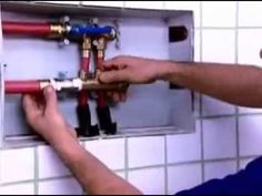 a man is fixing a fire hydrant in a tiled wall with red and blue hoses