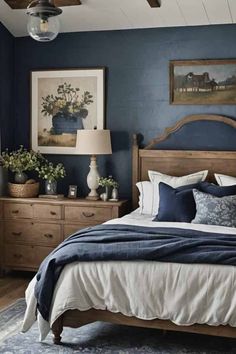 a bedroom with blue walls and white bedding, wooden furniture and pictures on the wall