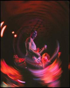 a man with a guitar in his hand and some people on the ground behind him