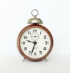 an alarm clock sitting on top of a white table next to a black and silver bell