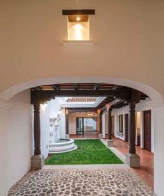 an archway leading into a house with grass in the front yard and stone steps on either side