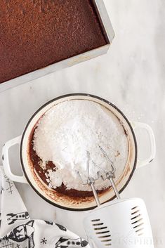 a cake in a pan with a whisk on the side next to it