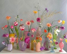 a white dresser topped with lots of vases filled with flowers