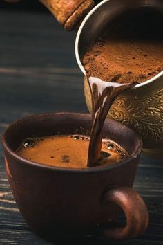 coffee being poured into a brown cup