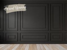 an empty room with black walls and wood flooring, painted in chalk paint that says grand opening