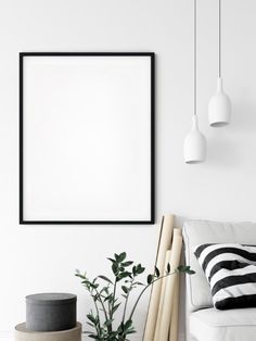 a white living room with black and white accessories on the floor, framed art above