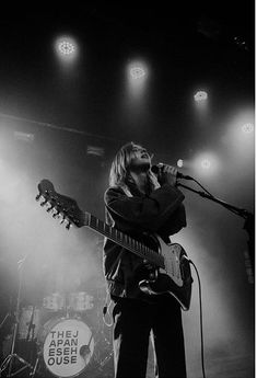 black and white photo of man playing guitar on stage