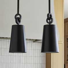 two black lamps hanging from the ceiling in a kitchen