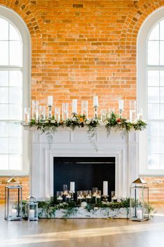 the fireplace is decorated with candles and greenery