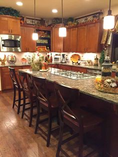 a kitchen with wooden cabinets and marble counter tops, along with bar stools that match the hardwood flooring