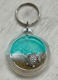 a glass keychain with a sea turtle in the sand on it's side