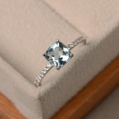 an engagement ring with a blue topazte surrounded by white diamonds in a box