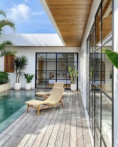 a chair sitting on top of a wooden floor next to a swimming pool in front of a house