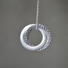 Stylish and timeless sterling silver interlocking circle pendant necklace. One ring has been hammered for a beautiful texture, and the other has been given a satin finish. The pendant hangs on a sterling silver belcher chain. Dimensions: Circles are approximately 2.5 cm (0.9") in diameter Metal: High quality 925 Sterling Silver The necklace will come in a beautiful gift box.  * CHECK OUT MORE JEWELLERY *   www.etsy.com/shop/kailajewellery Hammered Silver Jewelry For Wedding, Silver Hammered Necklace For Anniversary, Silver Metal Jewelry For Anniversary Gift, Silver Hammered Pendant Jewelry, Hammered Round Pendant Jewelry For Wedding, Wedding Jewelry Hammered Round Pendant, Modern Silver Chain Jewelry For Anniversary, Silver Full Circle Jewelry For Everyday, Hammered Round Pendant Wedding Jewelry