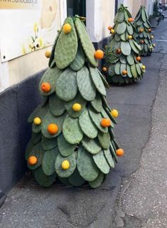 some very pretty looking fake cactus trees on the side of the road with oranges all over them