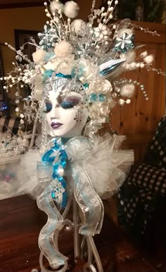 a white mask with blue and silver decorations on top of it, sitting on a table