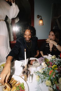 two women sitting at a table with plates of food and candles in front of them