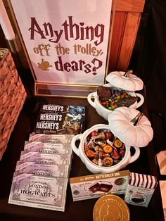 a table topped with candy and other items next to a sign that says anything off the trolly dears?