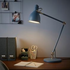 a desk lamp sitting on top of a wooden table next to a notebook and pen