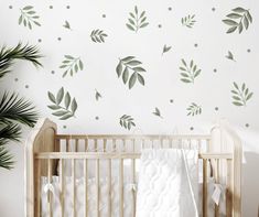 a baby crib in front of a wall with leaves on it