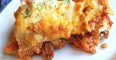 a white plate topped with lasagna covered in cheese