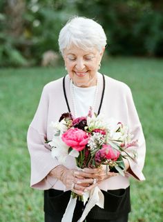 an older woman holding a bouquet of flowers