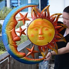 a woman holding up a sun and moon decoration