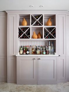 a bar with several bottles and glasses on the top shelf in a room that is painted white