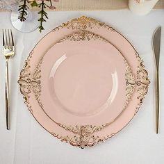 a pink plate sitting on top of a table next to utensils and silverware