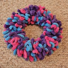 there is a purple and blue wreath on the floor with pink and blue yarn around it