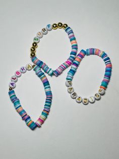 two bracelets with colorful beads and charms on them sitting next to each other in front of a white background