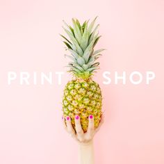 a woman's hand holding up a pineapple against a pink background with the words print shop