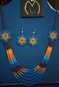 an assortment of beaded necklaces and earrings are displayed on a blue display case