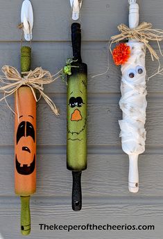 three halloween decorations are hanging on the side of a house, one is made out of toilet paper