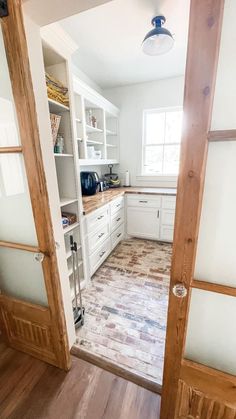 an open door leading to a kitchen with white cabinets and wood floors in the center