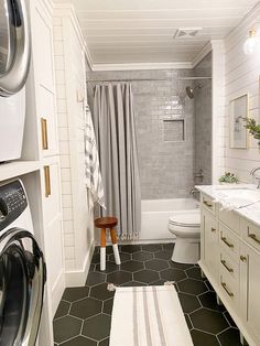 a washer and dryer in a white bathroom with black tile flooring on the walls