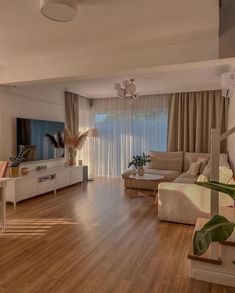 a living room filled with furniture and a flat screen tv on top of a wooden floor